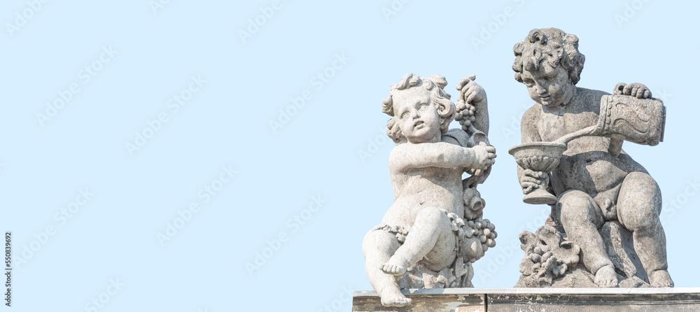 Fototapeta premium Banner with old sculptures of children playing with their toys in the historical downtown in Potsdam, Germany, with copy space and blue sky solid background. Concept of art and historical heritage