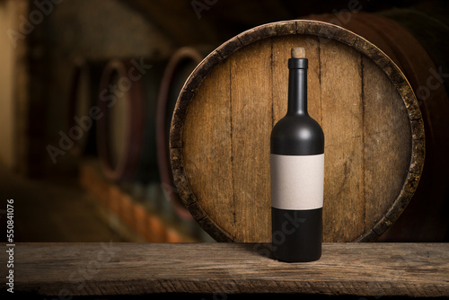 Excellent red wine bottles, wineglass, barrel and corkscrew on a rustic wooden table: traditional winemaking and wine tasting concept. High quality photo