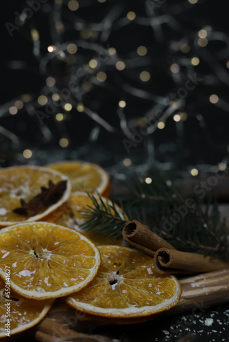 dried oranges cones cinnamon fir branches and star anise beautifully laid out on wooden natural sticks christmas decoration on a dark background with snow and garlands. for cards calendar labels signa