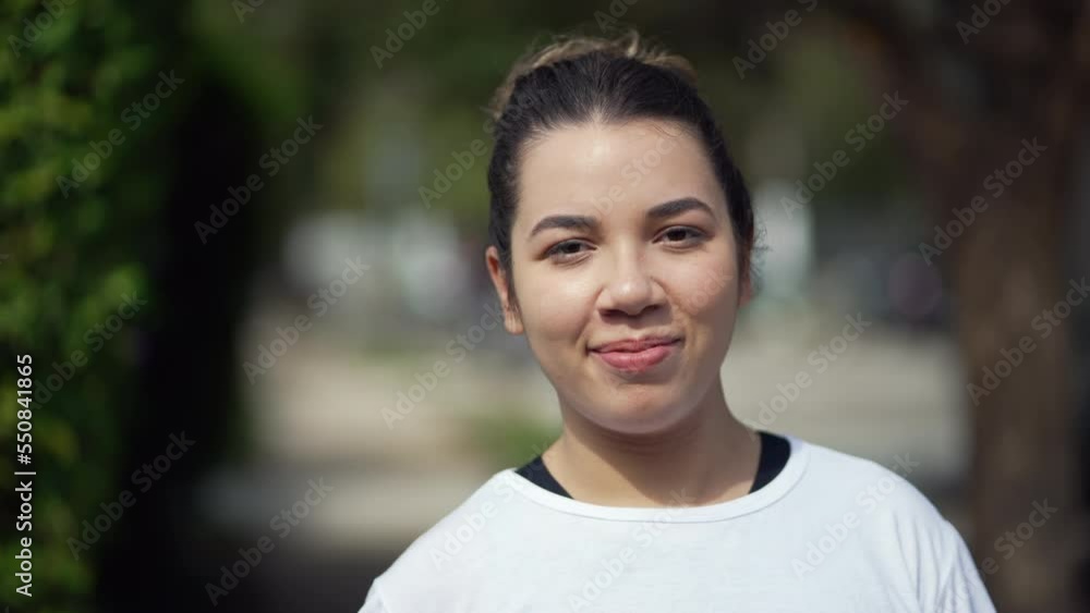 Happy young woman portrait face closeup walking outdoors looking at camera. Casual female person in 20s walks outside Happy young woman portrait face closeup walking outdoors looking at camera. Casual female person in 20s walks outside