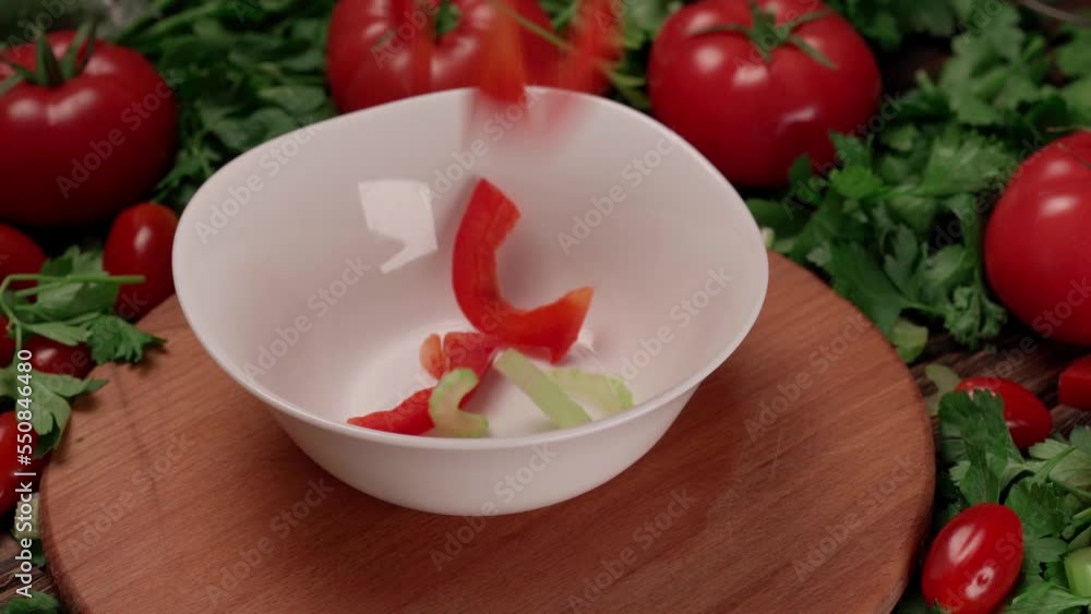 vegetables for salad falling into a white salad bowl. vegetables for salad falling into a white salad bowl.