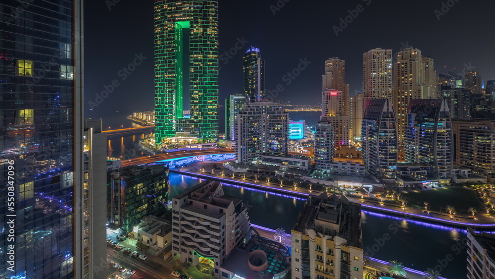 Panorama showing Dubai Marina skyscrapers and JBR district with luxury buildings and resorts aerial night timelapse