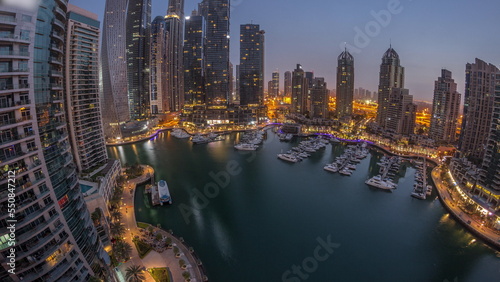 Dubai marina tallest skyscrapers and yachts in harbor aerial night to day timelapse.
