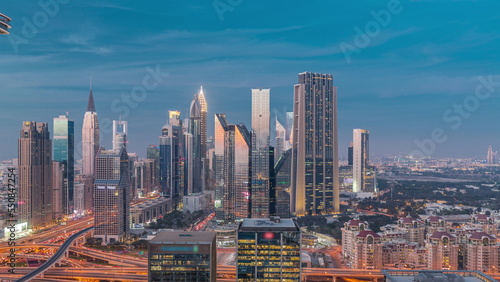Panorama of Dubai Financial Center district with tall skyscrapers with illumination day to night timelapse.