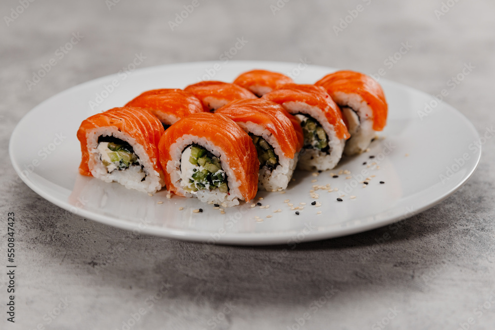 Eight servings of sushi with salmon and cucumber on a white plate. Eight servings of sushi with salmon and cucumber on a white plate.