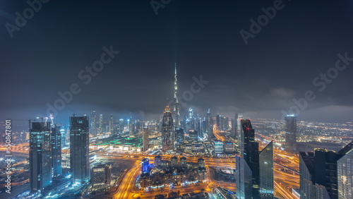 Aerial panorama of tallest towers in Dubai Downtown skyline and highway all night timelapse.