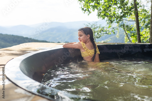 little girl in a hot tub in the mountains, summer