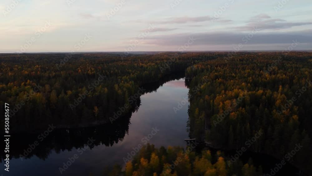 Aerial view around a mirroring forest lake on a sunny fall evening in Espoo, Finland - circling, drone shot Aerial view around a mirroring forest lake on a sunny fall evening in Espoo, Finland - circling, drone shot