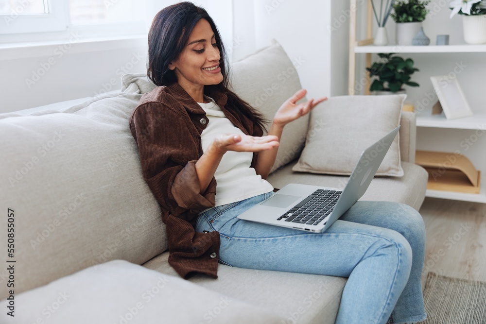 Woman freelancer on her day off sitting on the couch with a laptop at home and watching series and tv shows, smile Woman freelancer on her day off sitting on the couch with a laptop at home and watching series and tv shows, smile