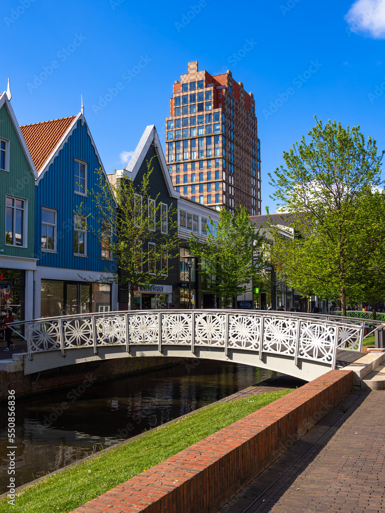 Naklejka premium Zaandam, Netherlands - April 26, 2022: Pedestrian Bridge over the water channel and traditional architecture of buildings in Zaandam, Netherlands