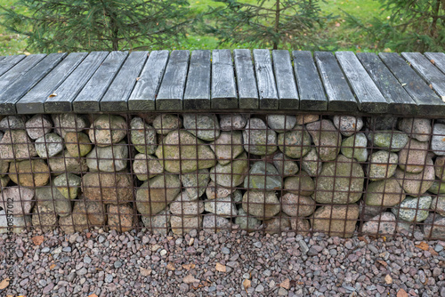 Modern garden bench around the fire pit made of gabion galvanized steel grid with granite stones photo