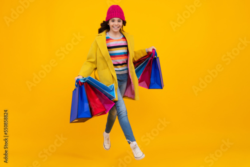 Funny teen girl hold shopping bag enjoying sale isolated on yellow. Portrait of teenager schoolgirl is ready to go shopping. Autumn shopping sale.