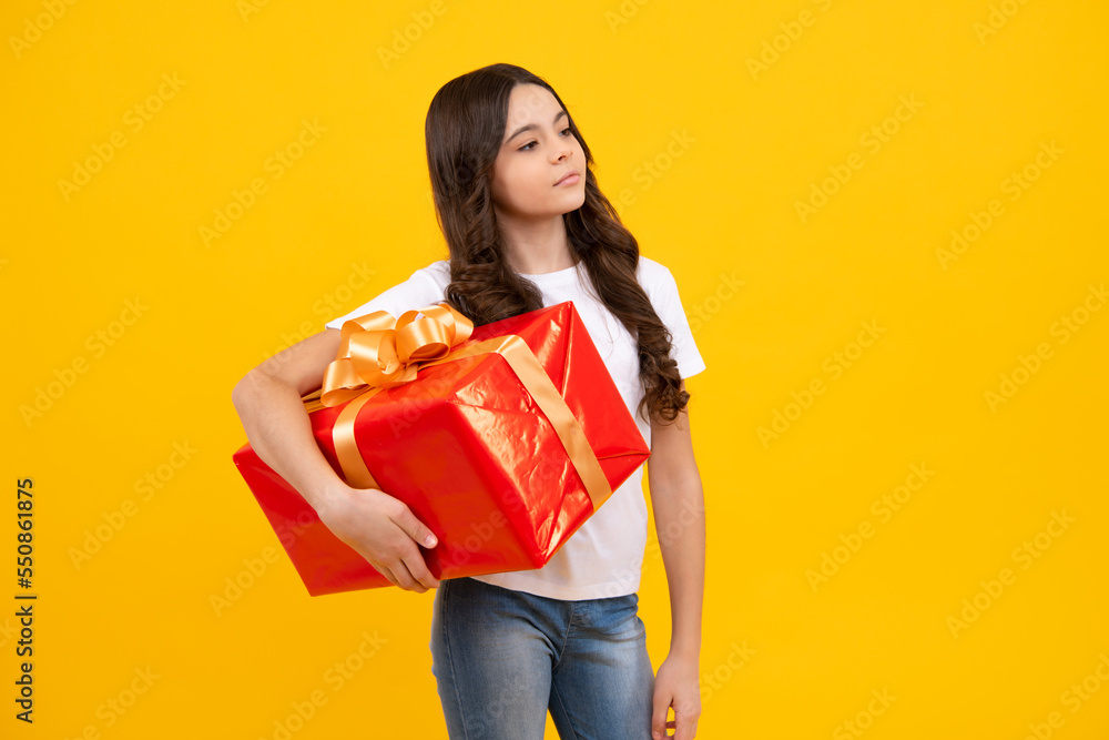 Portrait of a teenager child girl holding present box isolated over yellow studio background. Present, greeting and gifting concept. Birthday holiday concept. Portrait of a teenager child girl holding present box isolated over yellow studio background. Present, greeting and gifting concept. Birthday holiday concept.
