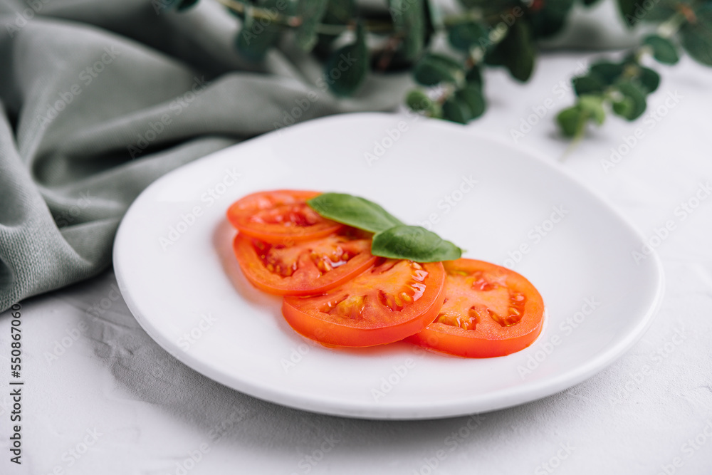 Sliced red tomatoes and basil leaves Sliced red tomatoes and basil leaves