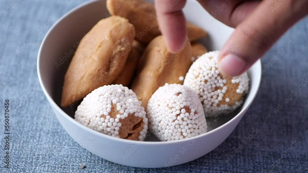 slow motion of hand pick indian sweet in a bowl on table. slow motion of hand pick indian sweet in a bowl on table.