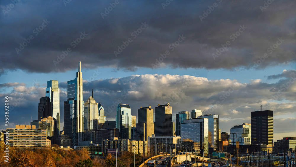 Obraz premium Skyline of Philadelphia (PA) USA at sunset under dark clouds, with copy space.