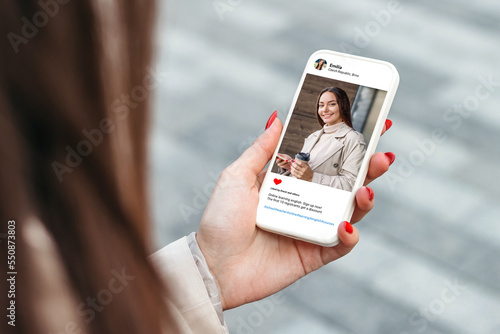 Woman looking at beautiful model's photo on mobile phone