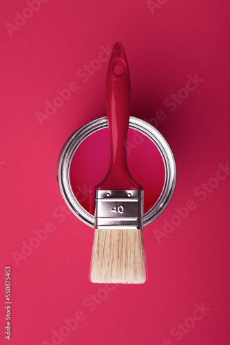 Can of viva magenta paint wirh brush on pink background. photo