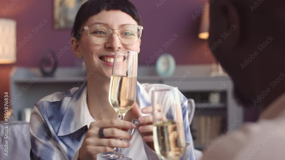 Young fancy African American couple toasting with champagne glasses while sitting at festive dinner table with friends Young fancy African American couple toasting with champagne glasses while sitting at festive dinner table with friends