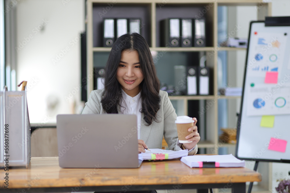 Attractive young Asian businesswoman working with laptop on her office desk.