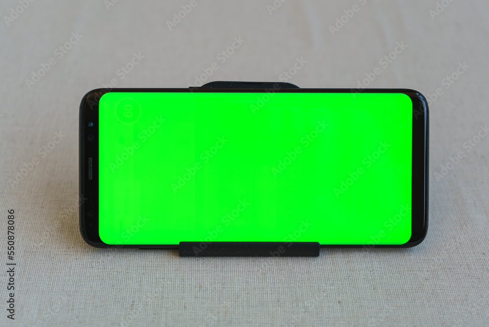 Mobile phone on table horizontally with green screen Mobile phone on table horizontally with green screen
