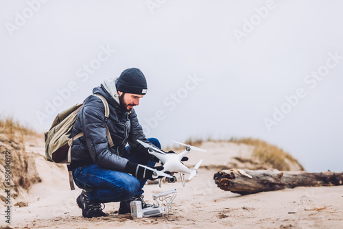 Man operating a drone while trekking on beach