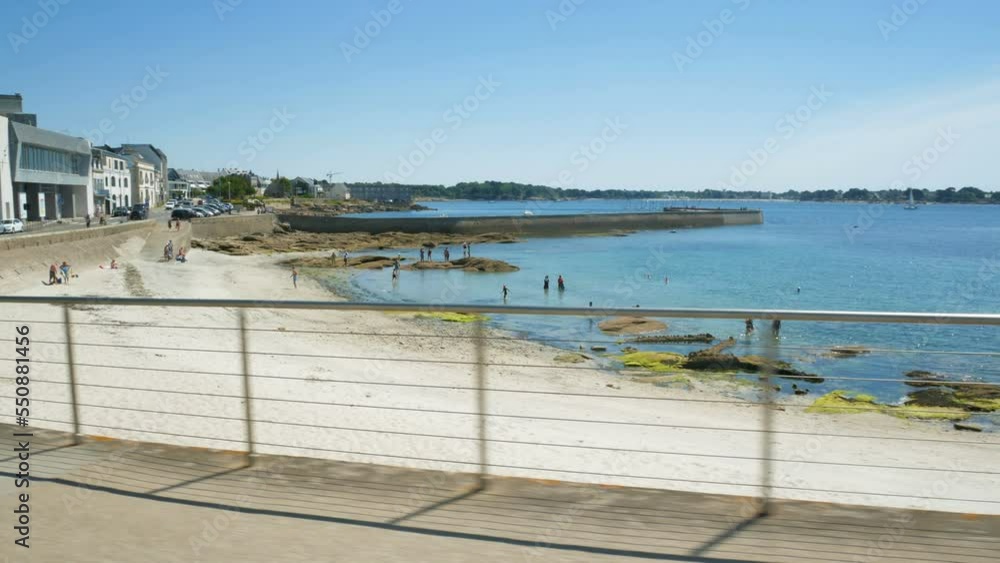 A small bay on the coastline of Concarneau, Brittany, France, with sands and the crystalline waters of the atlantic ocean. Families with kids are playing on the sand. A small bay on the coastline of Concarneau, Brittany, France, with sands and the crystalline waters of the atlantic ocean. Families with kids are playing on the sand.