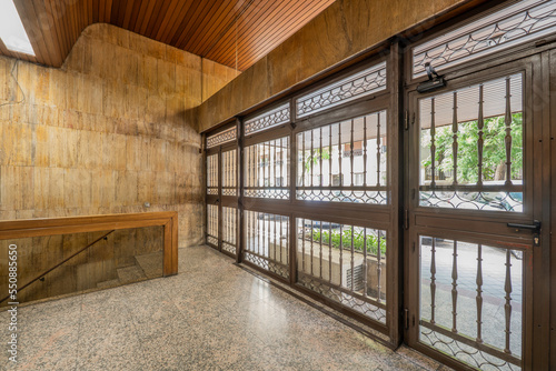 Interior of the portal of a house with tile and marble and granite floors, a metal portal and a modern wooden coffered ceiling © Toyakisfoto.photos