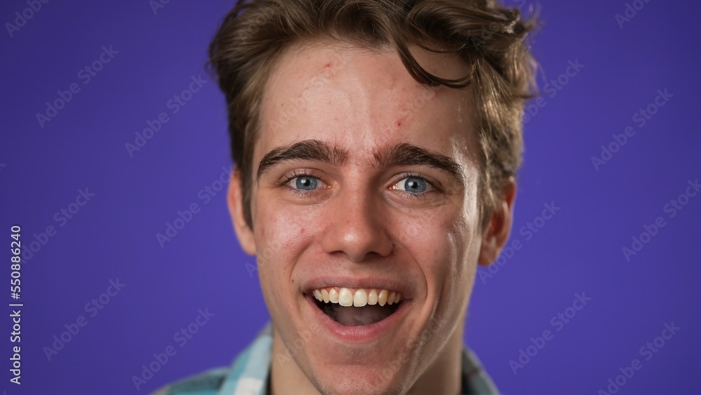 Closeup portrait of smiling happy young hipster man 20s isolated on solid purple background with copy space in studio