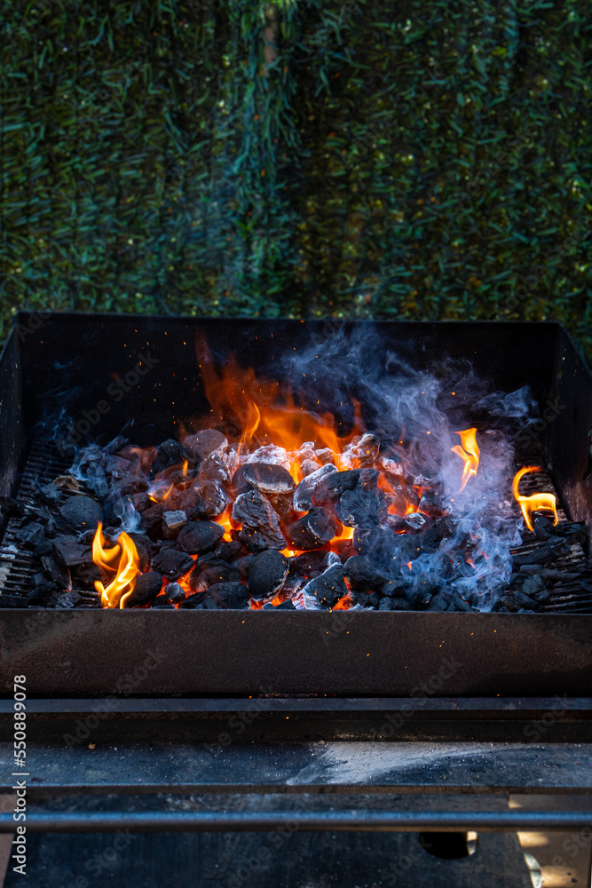 Charcoal and embers burning at full capacity at its peak in a metal barbecue and smoke Charcoal and embers burning at full capacity at its peak in a metal barbecue and smoke