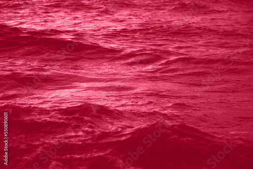 Viva Magenta toned sea water texture. Pool water with sun reflections. Trendy colour 2023 year.