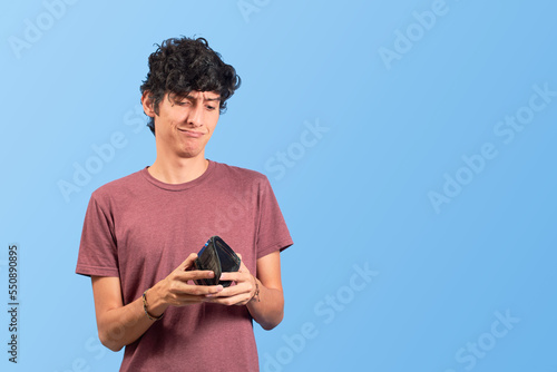 Φωτογραφία Broke young man with empty wallet on flat lay.