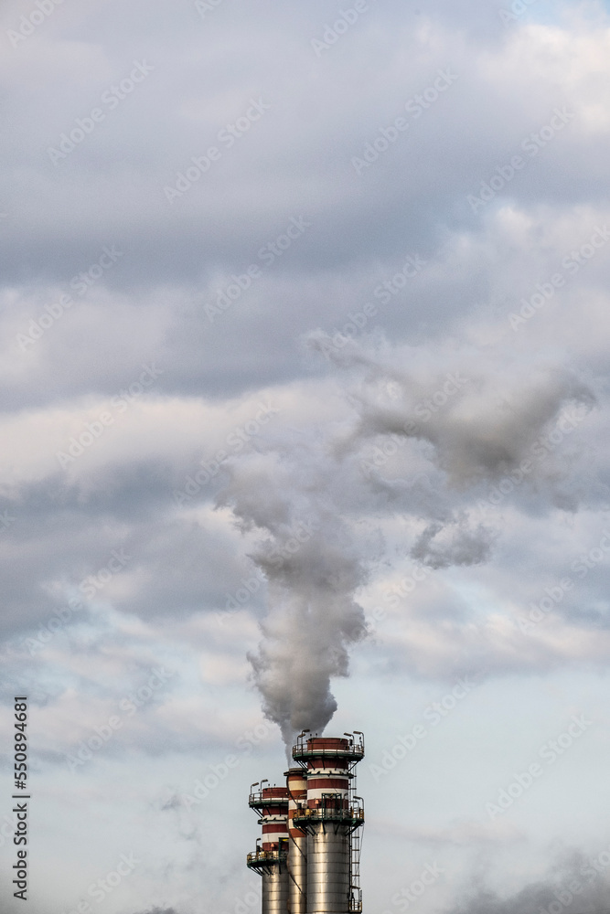 Smokestack exhaling smoke in a refinery with the sky in the background Smokestack exhaling smoke in a refinery with the sky in the background