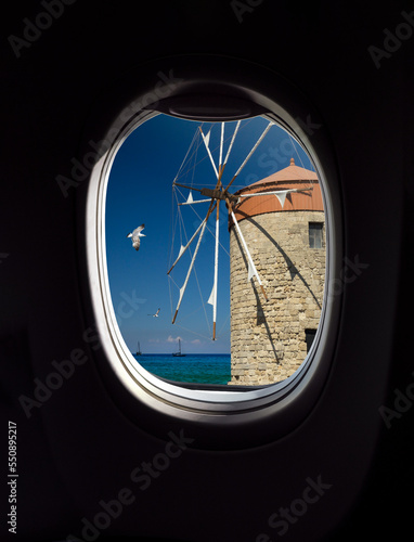 Greek windmill on Rhodes Island, Greece. Rhodes landmarks, view from porthole window of an airplane. Concept for travel company or airway transportation.