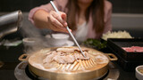 Woman Holding chopsticks, eating shabu, suki, hot pot at a Japanese restaurant