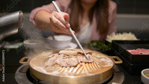 Woman Holding chopsticks, eating shabu, suki, hot pot at a Japanese restaurant