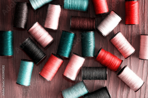 Pink and turquoise colored thread reels scattered on the tailor table. Embroidery theme backgrounds