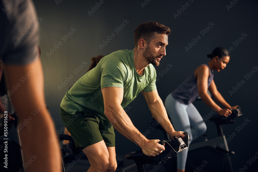 Fit man cycling during a gym class Fit man cycling during a gym class