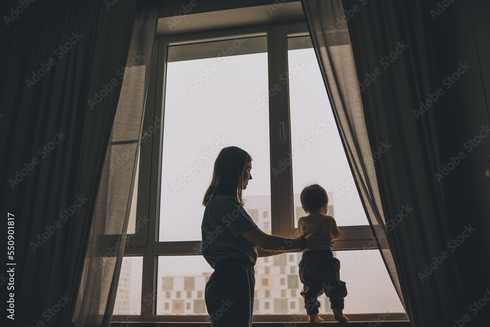 the silhouette of a mother and child standing near the window and looking into it