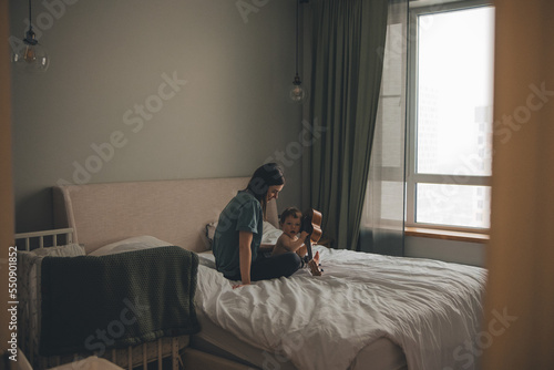 mom and baby are sitting on the bed in the bedroom and playing the ukulele  © Kate