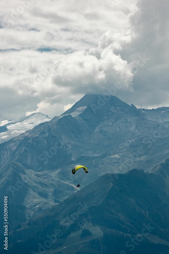Vertical shot of a man on a paraglider with Schmittenhohe mountains in the background, Austria photo