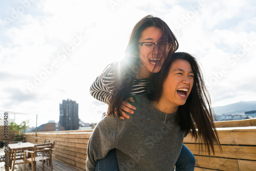 Two Chinese young girls in casual clothing having fun together on terrace.