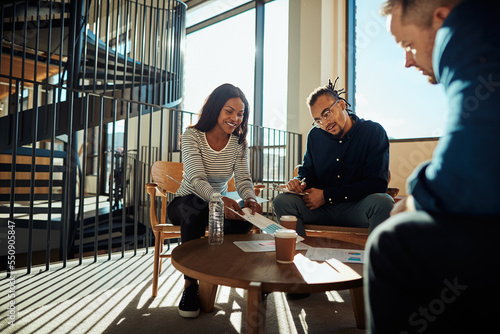 Two smiling African American businesspeople discussing paperwork with office colleagues