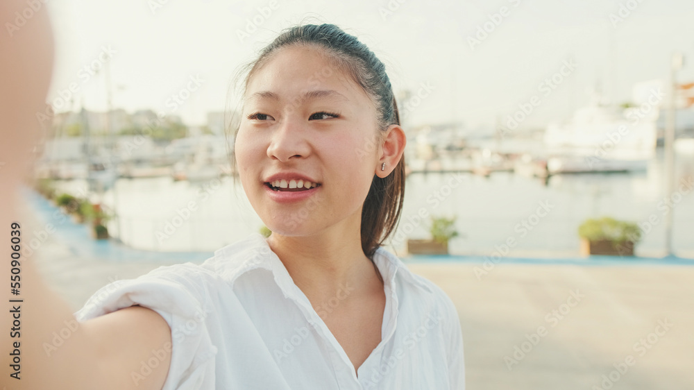 Young woman taking selfie on mobile phone on seascape background Young woman taking selfie on mobile phone on seascape background