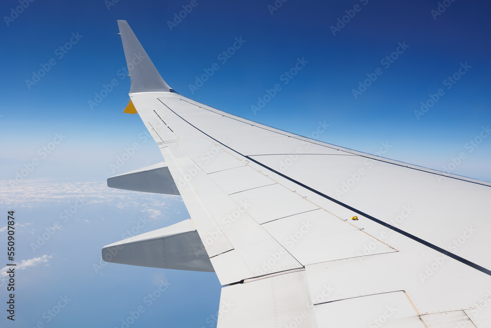 View from Inside an Aircraft: Window of the Cabin, White Airplane Wing and Clouds