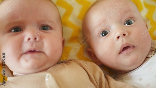 two twins lie in a bed. happy family kid dream concept. cute twins lie in fun bed in the bedroom in the evening smile look at the toy newborn boy and girl brother and sister