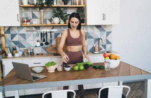 Cheerful woman preparing healthy breakfast with online video