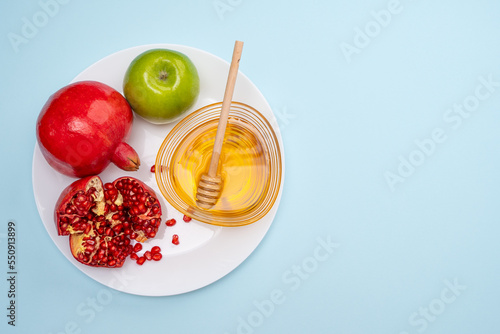 Jewish New Year Rosh Hashanah Traditional blue background with green apple, pomegranate and honey on a plate