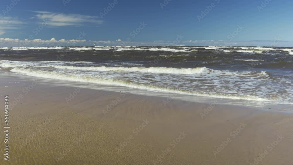 Movement from beautiful clouds to waves on a sandy shore. The storm throws branches and tree bark onto the yellow beach. High waves in the Gulf of Riga, Baltic Sea. Latvia Movement from beautiful clouds to waves on a sandy shore. The storm throws branches and tree bark onto the yellow beach. High waves in the Gulf of Riga, Baltic Sea. Latvia