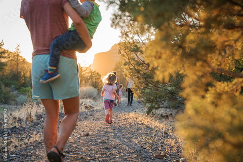 A mom walks with kids down a trail at sunset photo